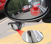 Car left side mirror along with blind spot parking mirror, 2 more cars in mirror, person is sit near car tyre